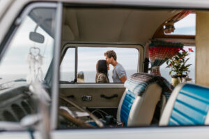 Man kissing woman on forehead near a camper van