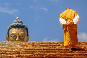 Buddhist monk climbing stairs toward statue of the Buddha