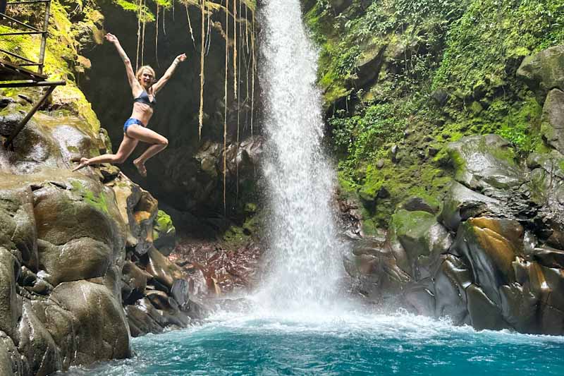 Woman jumping into a pool with waterfall