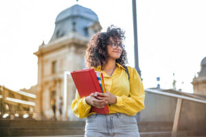 Smiling sober female college student holding books
