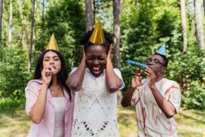 Three women with noisemakers at an outdoor party