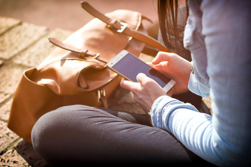 Woman with bag looking at a smartphone